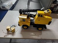 Side view of the yellow metal Tonka toy crane with the claw bucket detached and string visible.