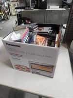 Photo of repurposed Panasonic toaster oven box filled with various music CDs stacked with visible covers.
