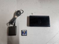 Nintendo DS console closed with charger and game cartridge shown