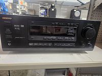 Front view of the Onkyo AV Receiver showing brand name, display panel, and input selections.