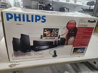 Box of Philips HTS3555 DVD home theater system showing product image, 1000W power, dock for GoGear and iPod, USB drive support, and Dolby Digital Surround.