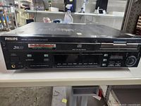 Front view of Philips black mult-disc audio CD player and recorder showing disc tray, playback controls, and power button.