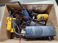 Top view of the box showing multiple walkie talkies and radios bundled with wires inside a cardboard box.