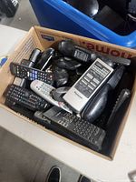 Top-down view of multiple remote controls in a small moving box