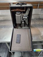 Open case showing the Revere Eight projector inside, with internal fabric flap and spool holder visible.