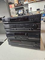 Stack of four Sony stereo components with visible buttons, volume knob, and display panels on a table.