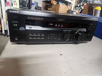 Front view of Sony digital AV receiver STR-DE215, showing model, control buttons, display, and volume knob.