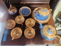 Top-view of tea set components including teapot, sugar pot, creamer, cups, and saucers.