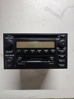 Front view of the Toyota car stereo showing power/volume knob, buttons, display, cassette deck slot, and function keys.