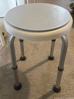 Side view of shower chair showing seat, legs, and rubber tips