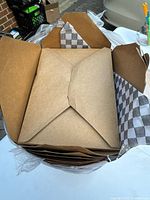 Open stack of brown kraft takeout boxes with checked liners visible