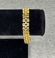 Bracelet wrapped on display showing triple-row gold-tone rectangular links