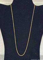 Full view of gold-tone link chain necklace draped on display bust