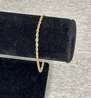 Gold-tone rope chain bracelet displayed on black stand