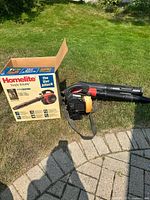 Blower/vacuum with strap beside original box on lawn