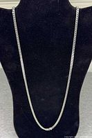 Full view of silver-tone woven chain necklace on display bust