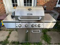 Front view of stainless Nexgrill 720-0830D propane grill with closed lid and side shelves