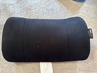 Front view of black ObusForme cushion showing overall shape and fabric tag