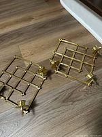 both brass candleholders on floor showing lattice design