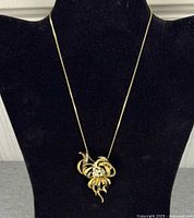 Front view of gold-tone flower pendant necklace on display bust