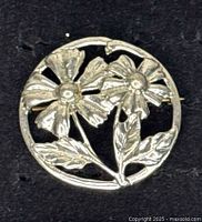 Front view of round sterling silver brooch with two flowers and leaves