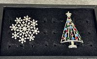 Front view of snowflake and Christmas tree rhinestone pins in display tray