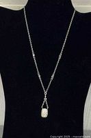 Full view of silver-tone chain necklace with rhinestone pendant displayed on black bust