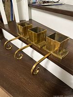 Three brass stocking holders on stair tread, showing full view with hooks
