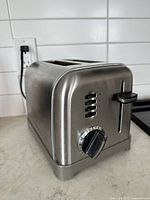 Photo of stainless steel 2-slice toaster showing side view with control buttons and browning dial.