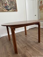 Overall view of teak dining table in extended oval form