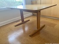 Side view of oak table showing T-shaped pedestal base, tabletop and leg design