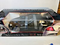Front view of the boxed black Mercedes-Benz SLR McLaren model with gullwing doors open and visible inside the clear plastic display box.