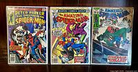 Front view of three vintage Spider-Man comic books: The Spectacular Spider-Man #7, Amazing Spider-Man #179, and issue #90, all bagged and boarded.