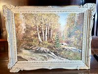 Frontal photo of the framed oil painting showing a forest landscape with stream, birch trees, and rocks.