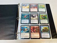 Open binder album displaying nine Magic: The Gathering cards in individual protective sleeves, spread across three rows and three columns. Cards detail various creatures and spells with colorful artwork.