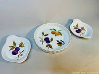Overview photo of three porcelain serving pieces with Evesham fruit pattern showing two smaller leaf-shaped dishes and one larger round dish.