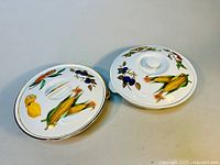 Two Royal Worcester Evesham covered serving dishes, tops visible with fruit and vegetable illustrations.
