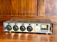 Front view of the Shure microphone mixer showing all control knobs, switches, and VU meter on wooden surface.