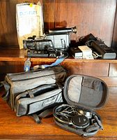 Sony Handycam camcorder with viewfinder and various accessories including carrying cases, batteries, and charger on a wooden shelf.