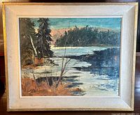 Frontal view of the framed oil painting showing the full artwork with river and trees, signature visible lower left.