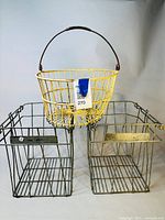 Three chicken egg baskets: two rectangular steel wire baskets and one oval yellow rubber-coated wire basket with handle.