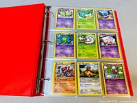 Photo showing red binder album open to nine Pokemon cards including Arbok, Kangaskhan, and Duskull