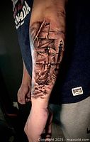 Photo of a tattoo of a sailing ship on a forearm demonstrating detailed realism and shading.