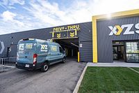 Exterior photo showing a van parked under the drive-thru loading zone at an XYZ Storage location with visible signage.