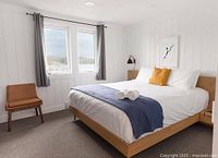 Guest room with queen bed, window view of lake, blue throw and wall art