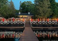 Exterior dusk view of lakeside deck and main building with string lights and dock