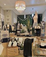 Interior display of Sweet Pea Boutique showcasing folded clothing, handbags, mannequins dressed in casual and chic outfits, and home decor items.