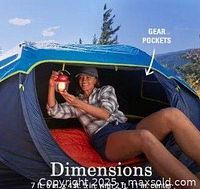 Photo showing tent entrance open with person inside, holding a lantern, showing gear pockets and dimensions.
