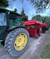 Photo showing a large green tractor attached to a red covered wagon ride, part of the playland attractions.