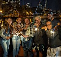 Group of six people posing with pirate swords and lanterns at night on a ship deck, representing the immersive escape experience.